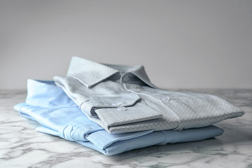 Classic shirts on marble table against light background