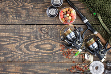 Fishing rods and spinnings in the composition with accessories for fishing on the old background on the table