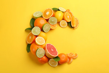 Letter C made with citrus fruits on yellow background as vitamin representation, flat lay