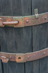 Closeup of rusted brass details with peeling green paint on a vintage rustic wine casket. Dark cold brown wooden barrel shot in daylight during winter season.