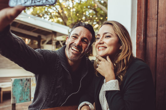 Smiling couple taking selfie at cafe