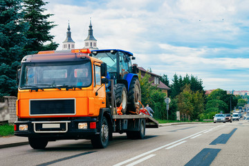 Fototapeta na wymiar Truck trailer transporter with hauler carrying agricultural tractor on the road in Poland.