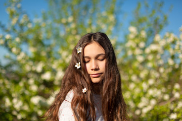Naklejka premium Portrait of a young beautiful teenager girl in a blooming spring green garden