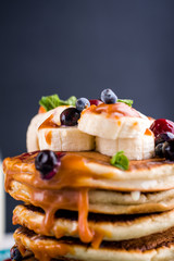 Delicious, healthy, hearty breakfast on the white table. Eggs, oatmeal, milk, tea, banana toast, homemade salted caramel, pancakes with fruit, orange juice. Top