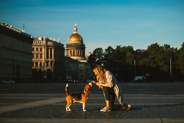 Obraz premium Pleasant woman hugging dog sitting on street in sunlight