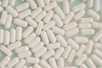 White medicine tablets background. Pills or medications drugs or supplements, top view, minimalism.