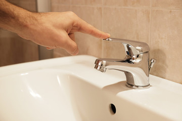 a person closes the water tap of the bathroom