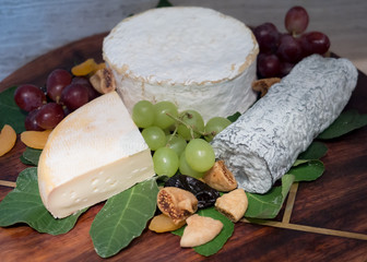Assortment of tasty and delicious cheese selection antipasto delicatessen. Reblochon, Brillat Savarin and Sainte Maure de Touraine on wooden board. Appetizer, party snack or good accompany with wine.