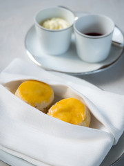 A tasty and delicious set of freshly baked scones with clotted cream and jam for afternoon tea or high tea party on a rustic wooden table. British way to relaxation and good time. Natural light.