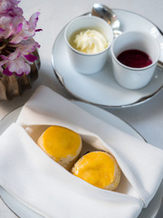 A tasty and delicious set of freshly baked scones with clotted cream and jam for afternoon tea or high tea party on luxury white porcelain china. British way to relaxation and good time. Natural light