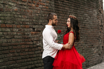 Obraz na płótnie Canvas Beautiful romantic couple. Attractive young woman in red dress and crown with handsome man in white shirt are in love. Happy Saint Valentine's Day. Pregnant and wedding concept.