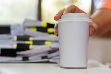 Paper coffee cup mock-up. Businessman holding white cardboard cup for logo with document paperwork on meeting. Concept of business people working in office and save world. Mockup for word