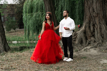 Beautiful romantic couple. Attractive young woman in red dress and crown with handsome man in white shirt are in love. Happy Saint Valentine's Day. Pregnant and wedding concept.