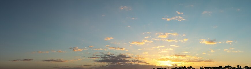 panoramic landscape showing the fiery burning colors of the sun setting in the clouds after a hot summers day in Australia