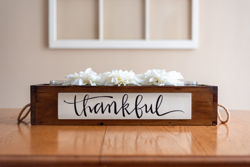 White flowers in a rustic wooden crate with the word thankful