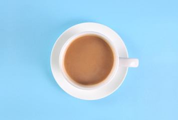 White cup of creamy coffee isolated on blue background. Top view.