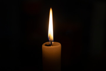 Candle flame in total darkness. A wax candle shines in flame. The wick burns. Church candle for...