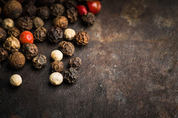 Mixed peppercorns on the rustic background. Selective focus. Shallow depth of field.