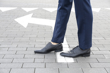 Young businessman going along road with arrow marking. Concept of choice