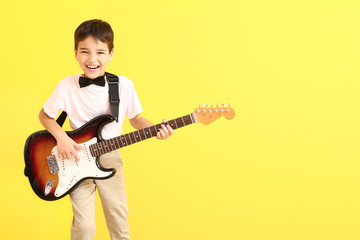 Obraz premium Little boy playing guitar on color background