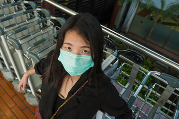 young beautiful and attractive Asian Chinese student at airport wearing protective facial mask...