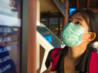 young beautiful and attractive Asian Chinese student at airport wearing protective facial mask...