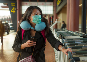 young beautiful and attractive Asian Chinese student at airport wearing protective facial mask against China Coronavirus epidemic outbreak spreading breathing syndrome