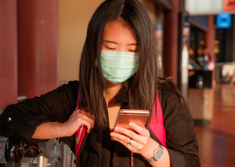 young beautiful tourist Asian Korean woman at airport wearing protective facial mask checking...