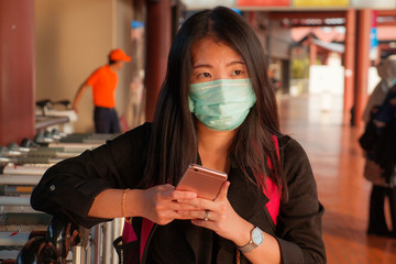 young beautiful tourist Asian Korean woman at airport wearing protective facial mask checking...