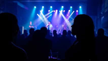 The crowd at the concert. Summer music festival. Silhouettes of concert performers on the stage in...