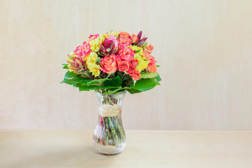 bouquet of flowers, colourful roses with green leaves standing in a glass vase