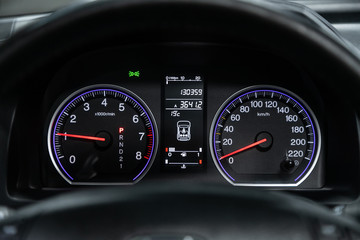 The dashboard of the car is illuminated by bright illumination. Speedometer, circle tachometer, oil and fuel level.