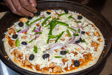 Worker preparing pizza topping 