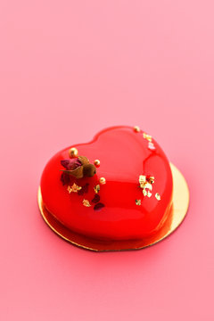 Cake. One small mousse  red cake  in heart shape  on a pink background. Vertical photo
