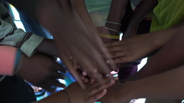 Arm stacked together one by one in unity and teamwork. Many hands getting together in the center of a circle. Close up outdoor shot. Many african children hands connecting, Tanzania, East Africa
