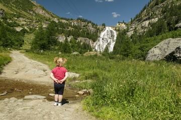 Rear View Of Baby Girl Standing Against Waterfall - obrazy, fototapety, plakaty