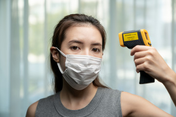 Woman  feeling sick wearing protective mask. With security's hand check at gates use digital...
