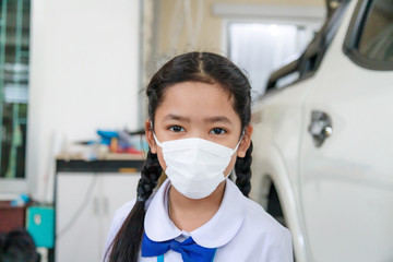 Obraz na płótnie Canvas Little Asian girl in Thai student uniform wearing virus protective flu mask, Health care concept, select focus shallow depth of field