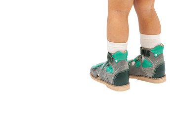 Baby feet in orthopedic shoes on white background