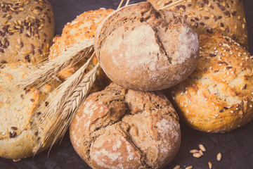Wholegrain rolls or bread with seeds and ears of rye grain. Vintage photo