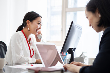 取引先に電話をかける女性社員 © Monet