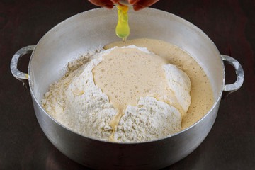 Adding egg to yeast dough for making buns.