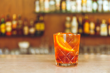 Glass of tasty alcoholic negroni cocktail with orange slice on bar stand. Festive concept.