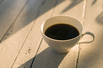 A cup of black coffee putting on the table as shadow and light.