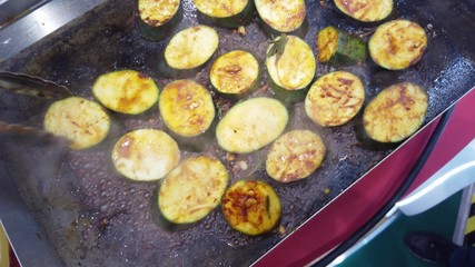 Roasting zucchini slices on a stove.