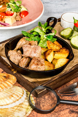 Potato with meat in a pan and fresh vegetables
