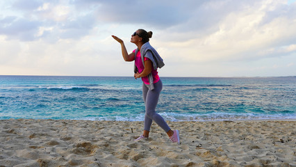 beautiful European girl in bright sportswear on the shore of the turquoise ocean. young girl posing on the background of the pacific ocean at sunset. Lifestyle, emotions, joy , happy.