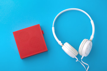 Red wireless speaker and white wired headphones