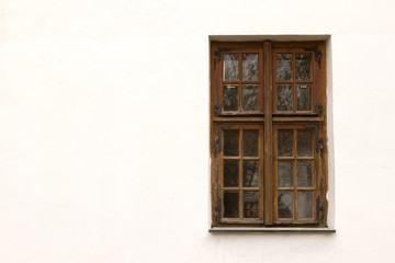 wooden brown window on a white plastered wall from the outside. window outside the house. copyspace. double-leaf window with window leaf, European style