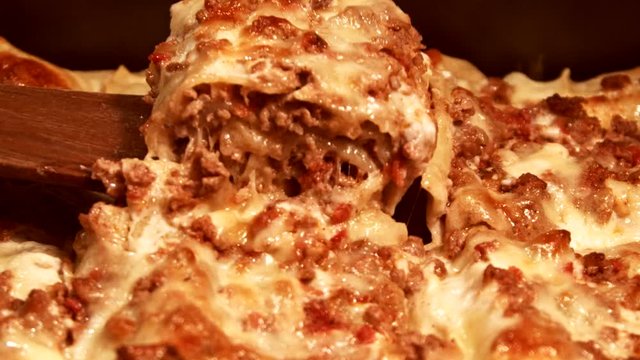 Cook takes a portion of fresh traditional lasagna 